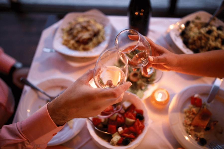 couple dining at a steakhouse and clinking wine glasses together